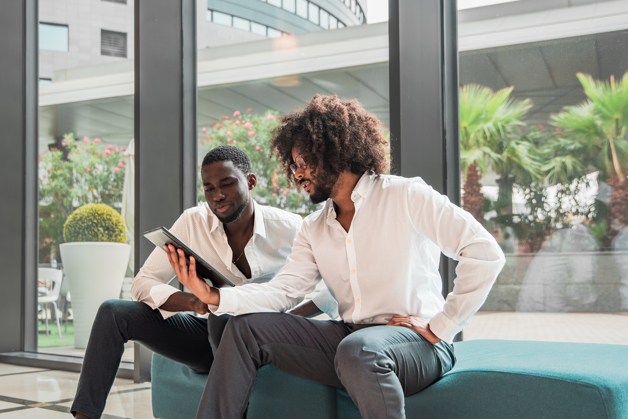 Professional African american Men Engaging in a Discussion with a Digital Tablet in an Office Lobby
